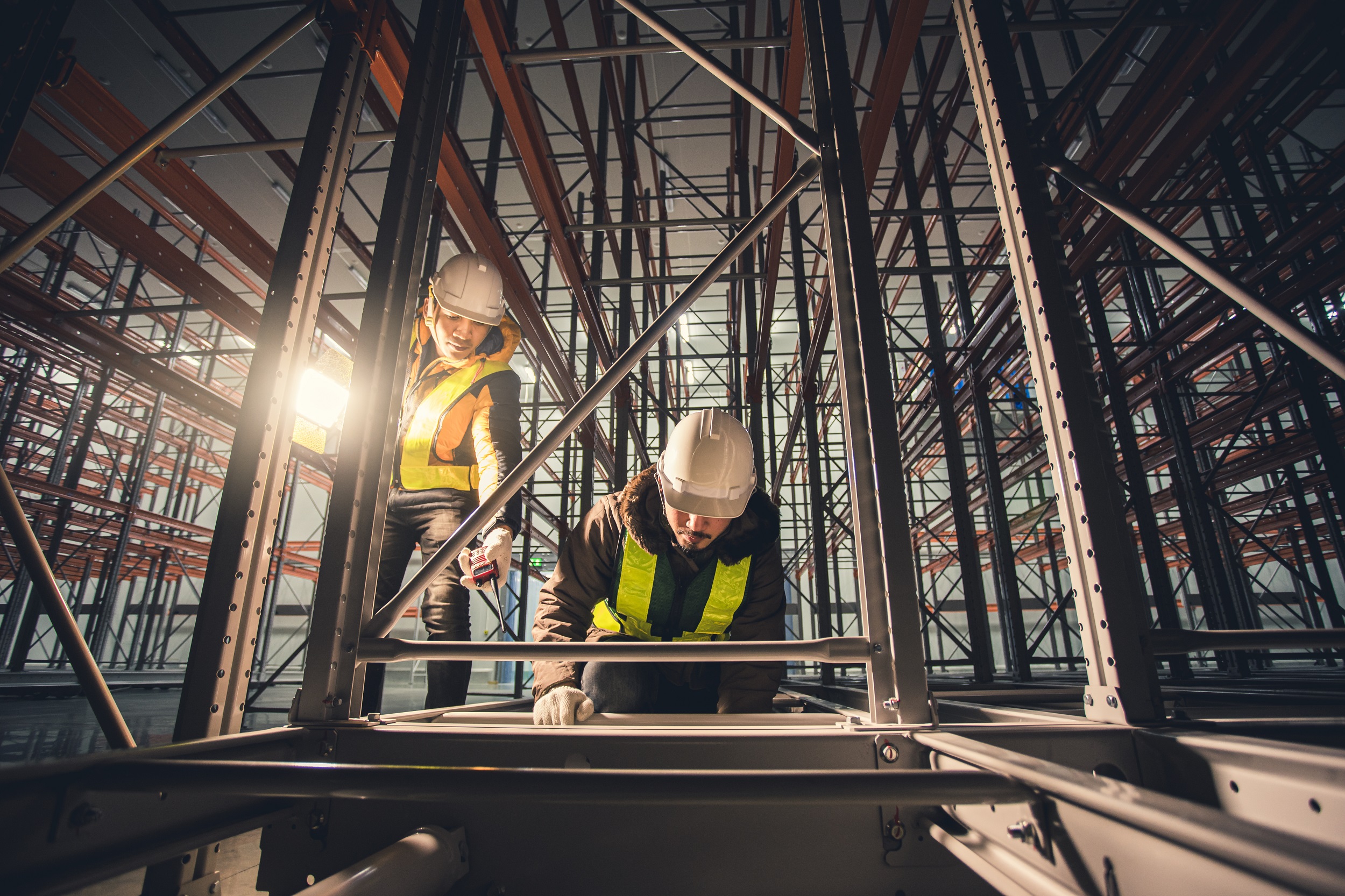 Two technician repairing machine shelf in dark room warehouse - E-distribution
